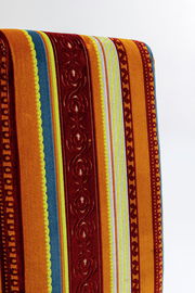 Rückansicht eines Stuhls mit buntem, gestreiftem Stoffbezug in warmen Farben.