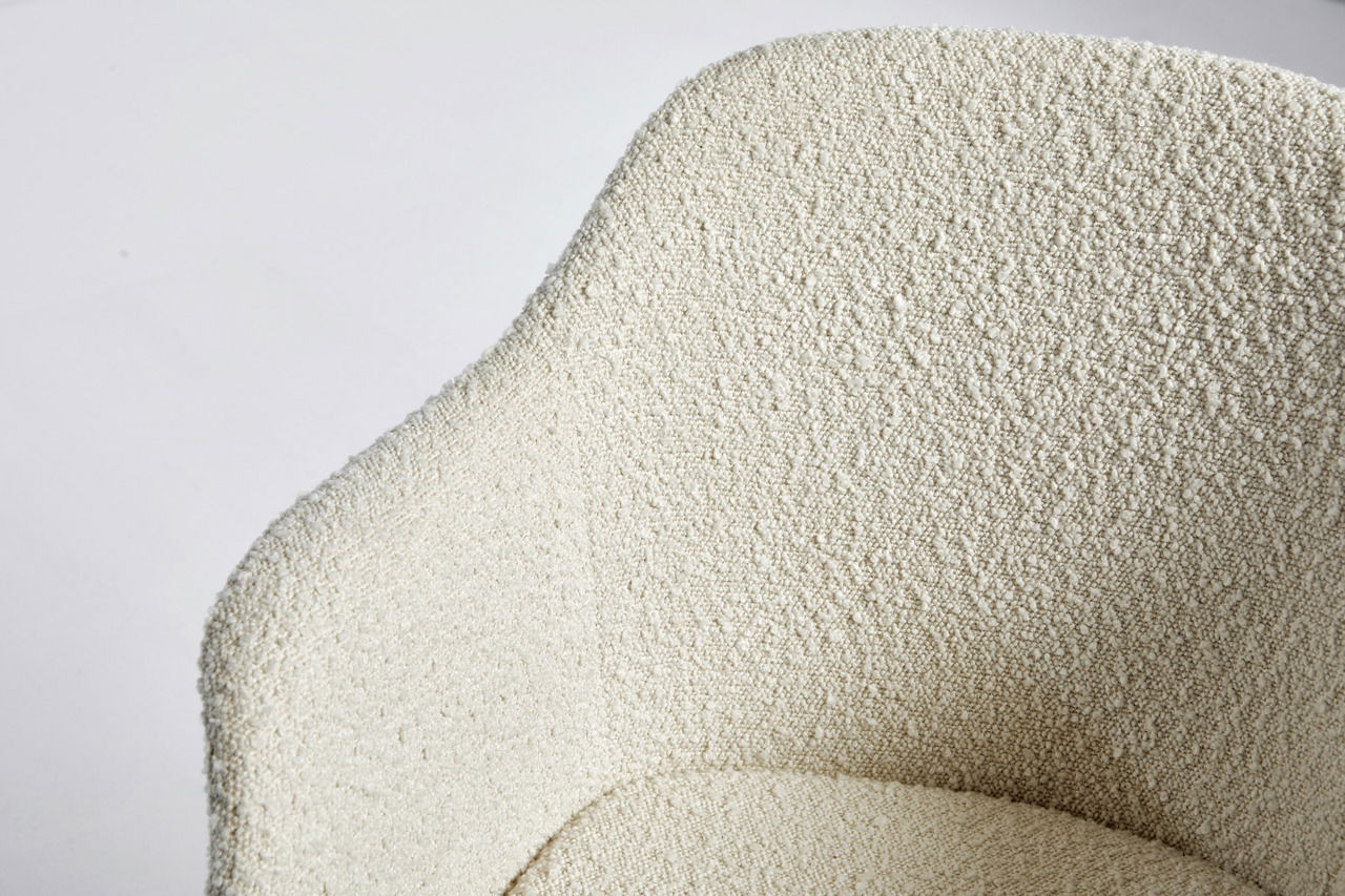 Nahaufnahme eines Bürostuhls mit strukturierter, cremefarbener Polsterung, von oben betrachtet.