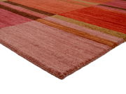 Wollteppich in warmen Rottönen mit geometrischem Muster, perspektivisch von der Ecke aufgenommen