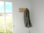 Holzgarderobenleiste an der Wand mit einem Mantel, seitliche Perspektive