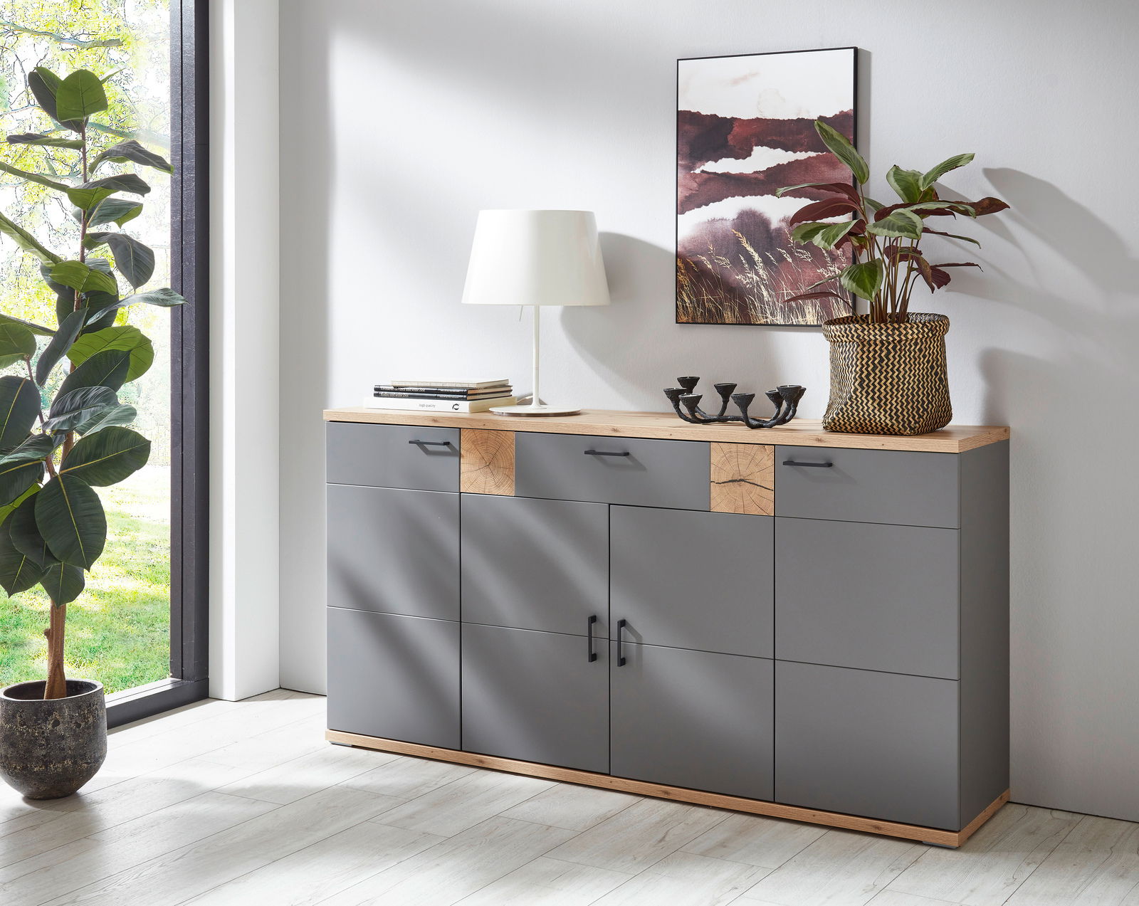 Modernes Sideboard in Grau mit Holzdetails, dekoriert mit einer Lampe, Büchern und Pflanzen, seitliche Perspektive.