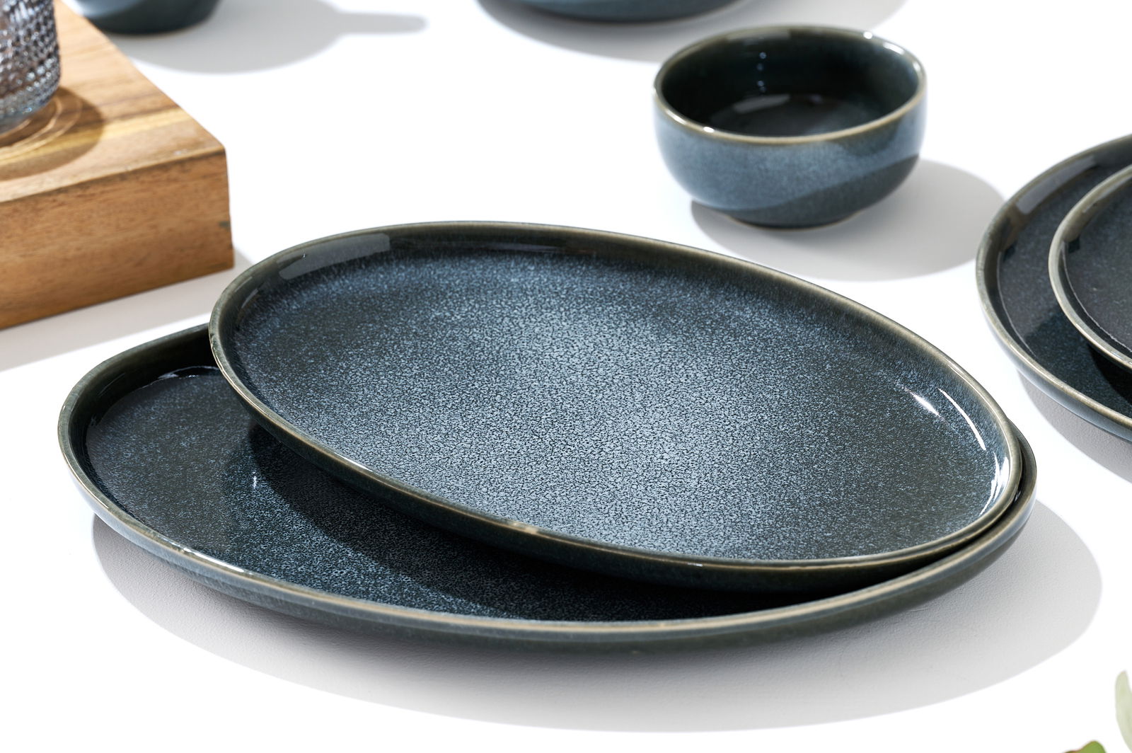 Zwei ovale, dunkelblaue Platten aus Keramik, übereinander gestapelt, in einer schrägen Perspektive fotografiert.