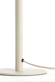 Nahaufnahme eines cremefarbenen Lampenfußes mit rundem Sockel und einem Kabel, das seitlich herausführt.