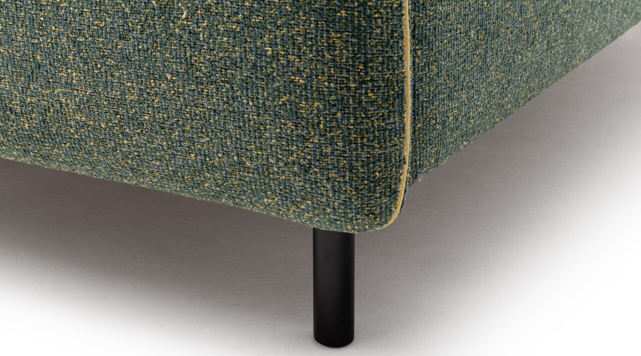 Nahaufnahme eines Polsterbetts mit grünem Stoffbezug und schwarzem Metallbein, seitliche Perspektive