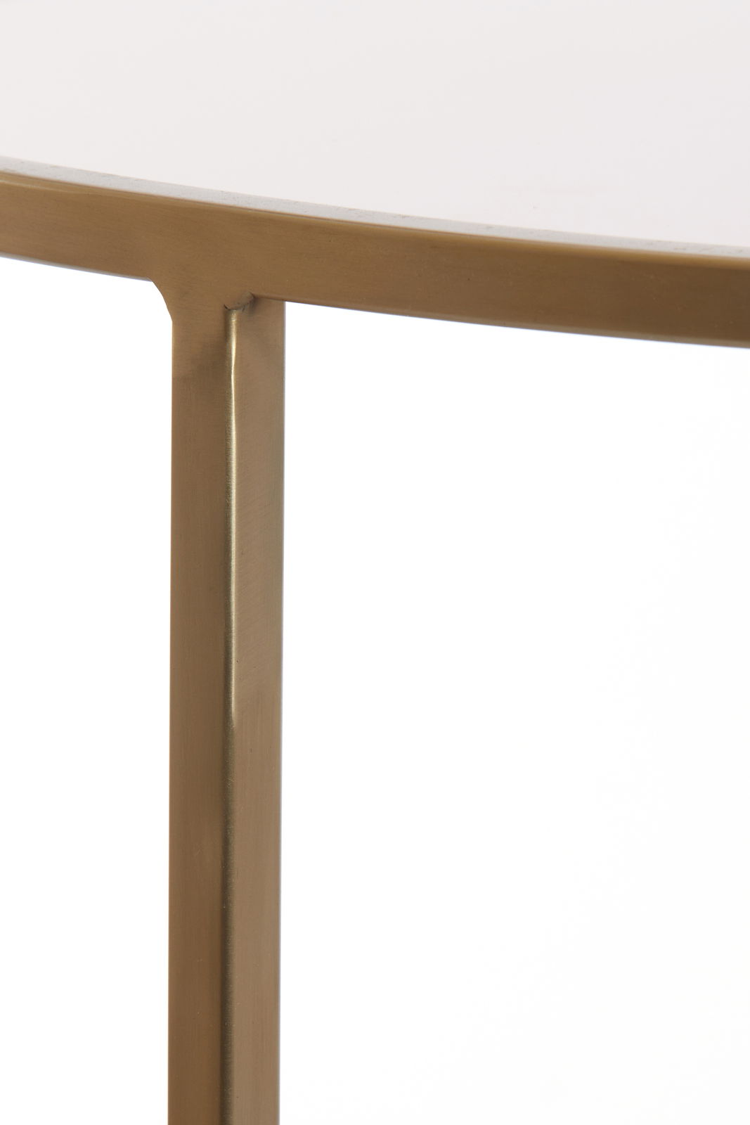 Nahaufnahme eines Couchtischs mit goldfarbenem Metallrahmen und weißer Tischplatte, seitliche Perspektive.
