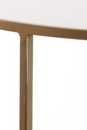 Nahaufnahme eines Couchtischs mit goldfarbenem Metallrahmen und weißer Tischplatte, seitliche Perspektive.