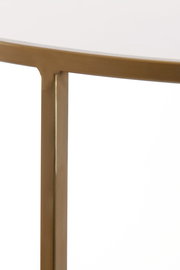 Nahaufnahme eines Couchtischs mit goldfarbenem Metallrahmen und weißer Tischplatte, seitliche Perspektive.