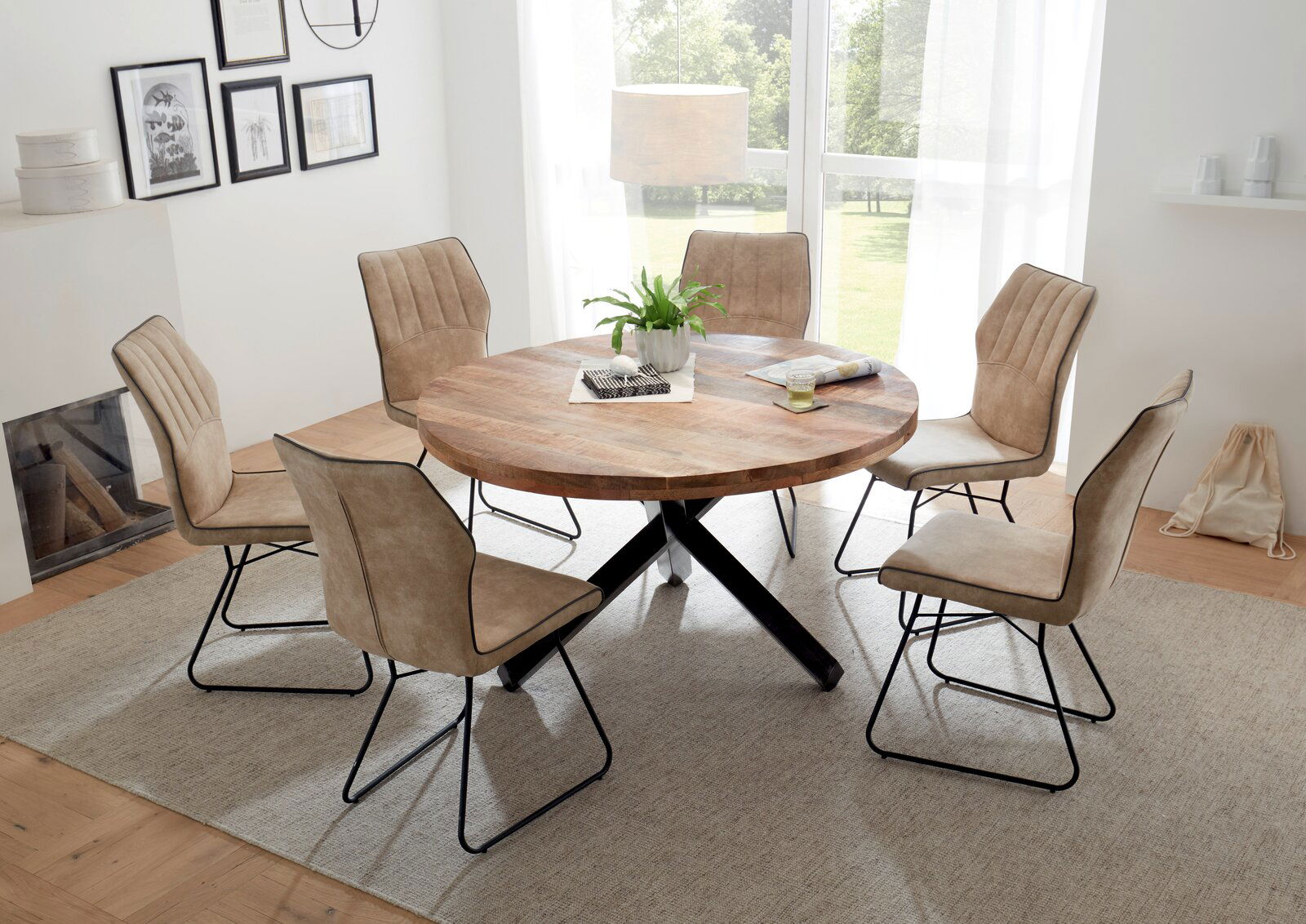 Runder Esstisch aus Holz mit schwarzem Kreuzfuß, umgeben von sechs beigen Stühlen, in einem hellen Raum mit großen Fenstern, aus der Vogelperspektive betrachtet.