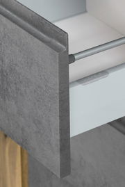 Nahaufnahme einer Schublade mit grauer, steinartiger Front und Metallgriff, perspektivisch von der Seite aufgenommen.