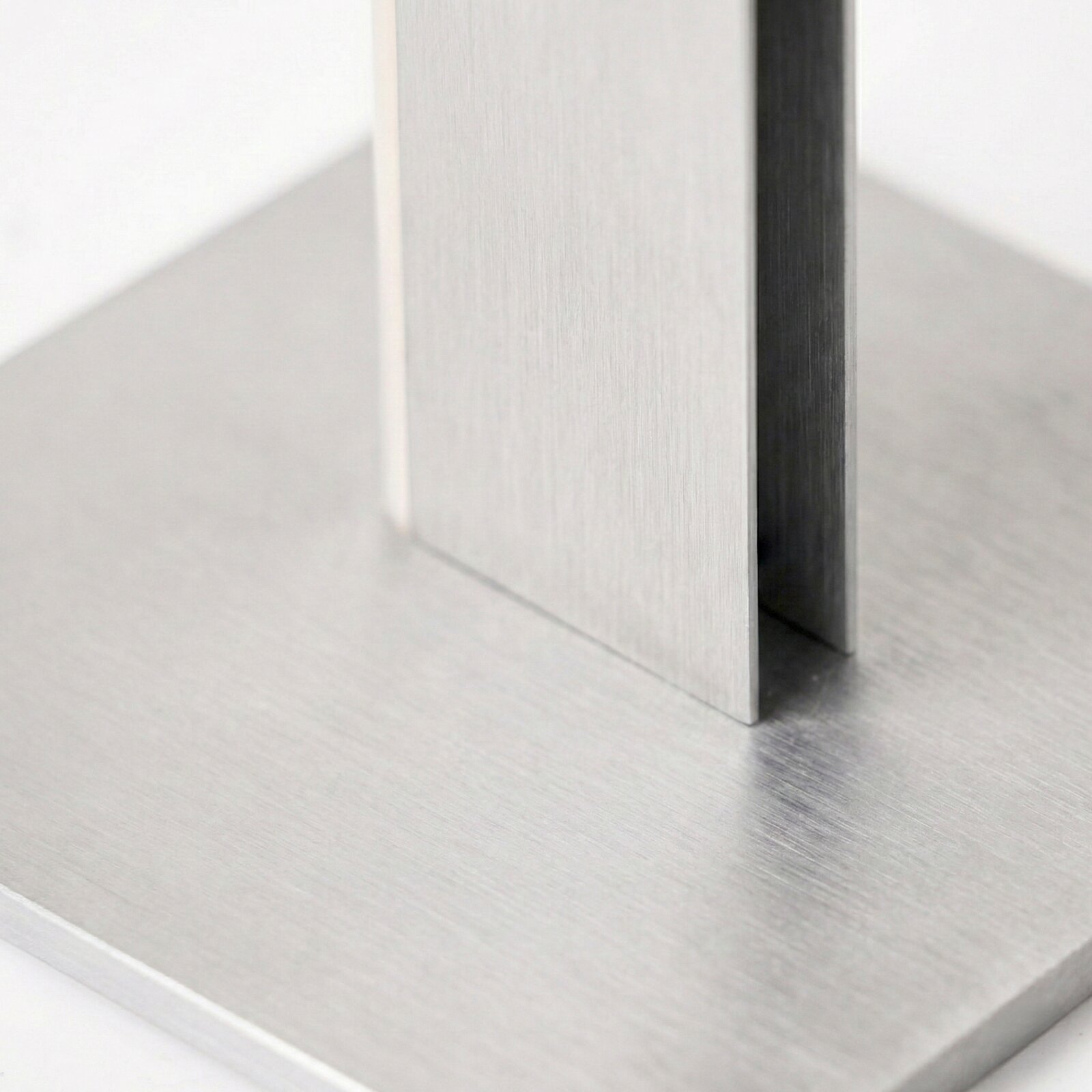 Detailansicht aus schräger Nahperspektive auf eine moderne Konstruktion aus gebürstetem Metall mit rechteckiger Bodenplatte und vertikalen Streben