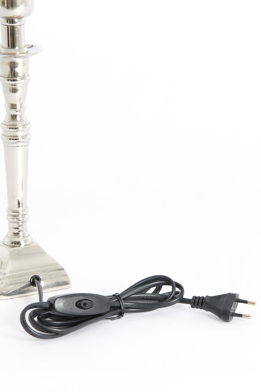 Nahaufnahme eines silbernen Lampenfußes mit Kabel und Schalter, seitliche Perspektive.