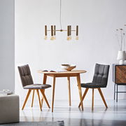 Runder Esstisch aus Holz mit zwei gepolsterten Stühlen in einem modernen, hellen Raum, seitliche Perspektive.