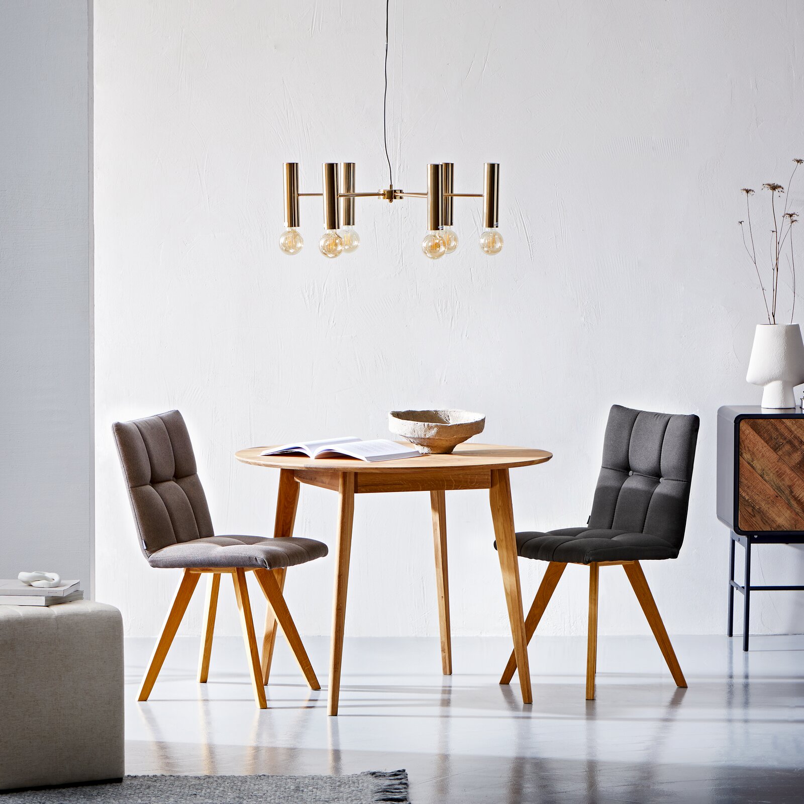 Cantus Esstisch TALLINN Runder Esstisch aus Holz mit zwei gepolsterten Stühlen in einem modernen, hellen Raum, seitliche Perspektive.