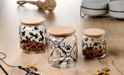 Drei Glasdosen mit Holzdeckeln, dekoriert mit Pfotenabdrücken und Knochenmotiven, auf einem Holztisch aus der Vogelperspektive.