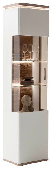 Moderne weiße Vitrine/Hochschrank mit Glasfront und LED-Innenbeleuchtung, Holzdeckplatte und Holzsockel, innen Glaseinlegeböden mit Gläsern und Deko, Perspektive: leicht schräg von vorn