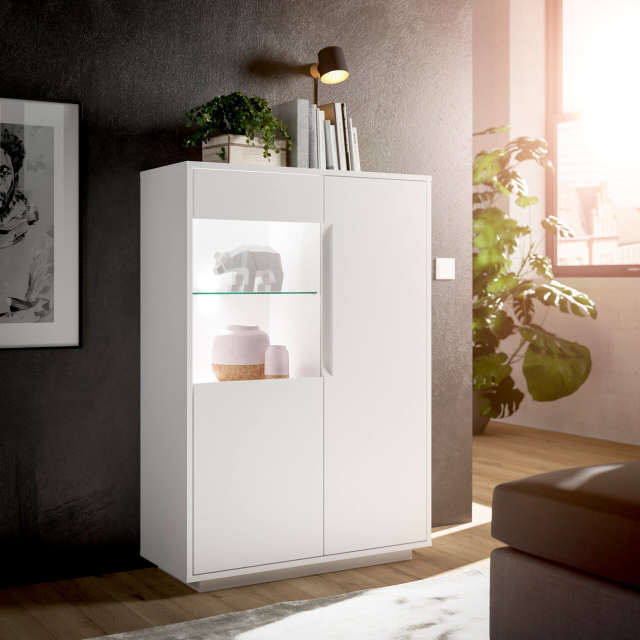 Modernes weißes Highboard mit Glasvitrine, dekoriert mit Pflanzen und Büchern, seitliche Perspektive
