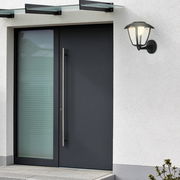 Moderne Akku-Außenwandleuchte an einer Hauswand neben einer Eingangstür, seitliche Perspektive