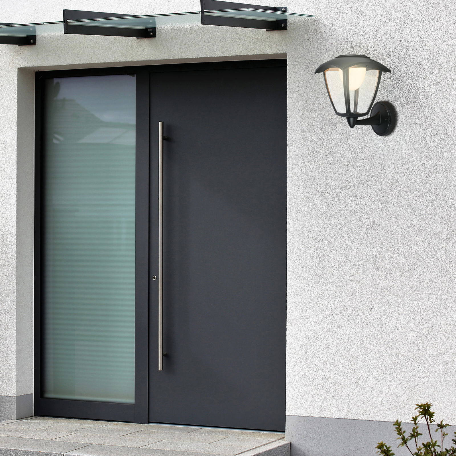 Moderne Akku-Außenwandleuchte an einer Hauswand neben einer Eingangstür, seitliche Perspektive