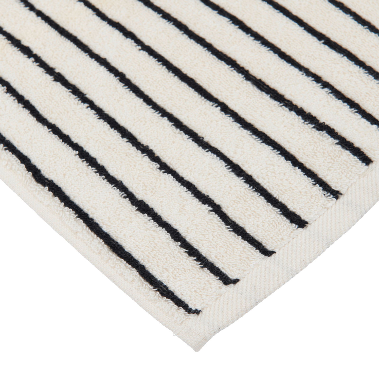 Nahaufnahme einer cremefarbenen Badematte mit schwarzen Streifen, diagonale Perspektive auf die Ecke.