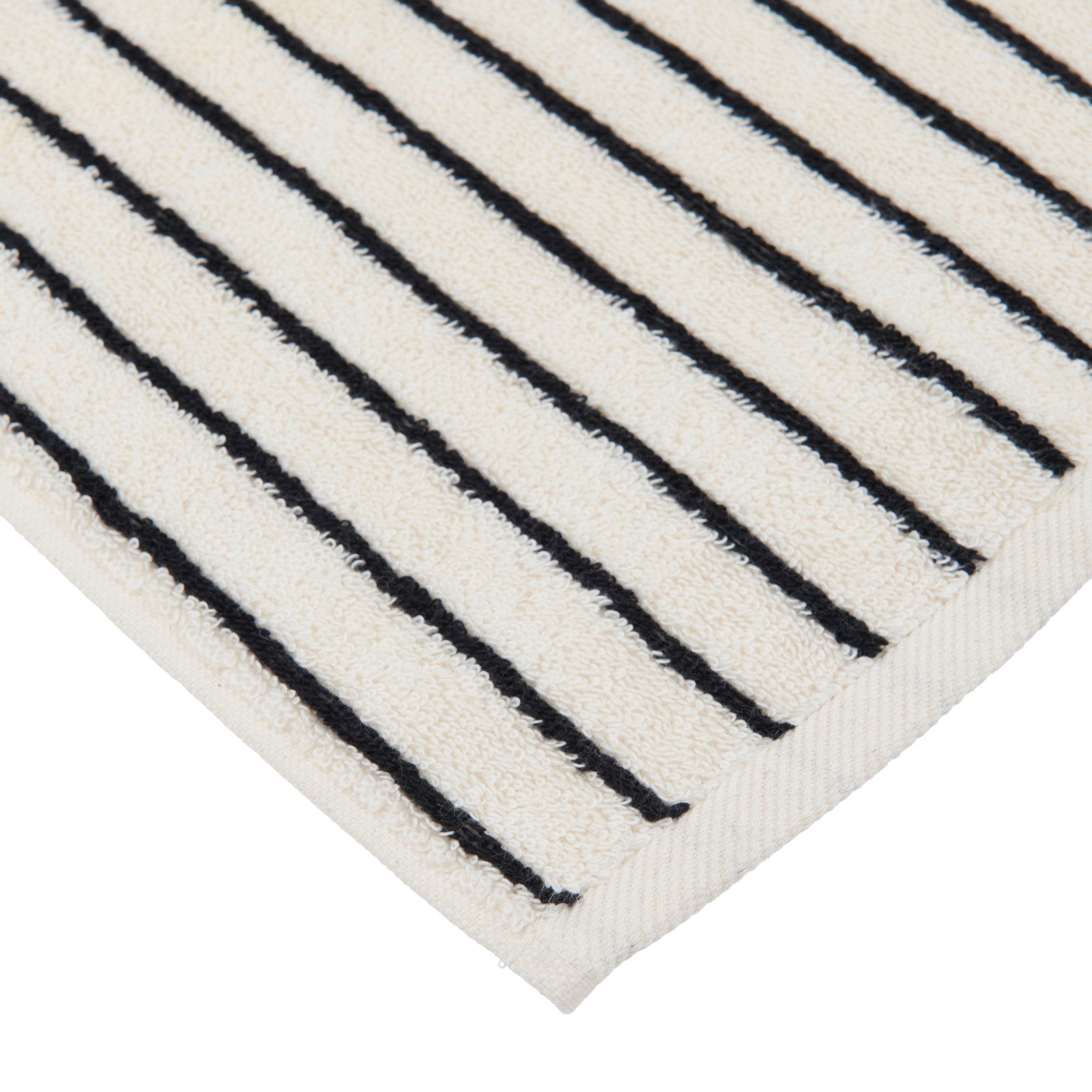 Nahaufnahme einer cremefarbenen Badematte mit schwarzen Streifen, diagonale Perspektive auf die Ecke.