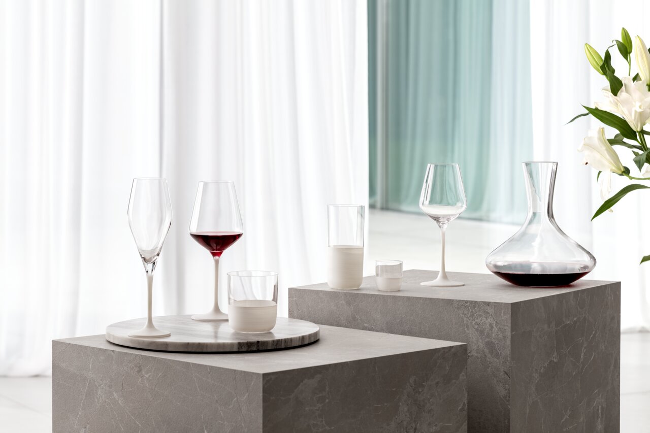 Villeroy & Boch Schnapsglas 4-tlg. MANUFACTURE ROCK BLANC Elegantes Schnapsglas-Set mit vier Gläsern auf einem modernen, grauen Podest, seitliche Perspektive.