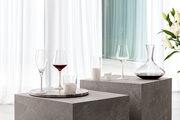 Elegantes Schnapsglas-Set mit vier Gläsern auf einem modernen, grauen Podest, seitliche Perspektive.