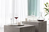 Elegantes Schnapsglas-Set mit vier Gläsern auf einem modernen, grauen Podest, seitliche Perspektive.