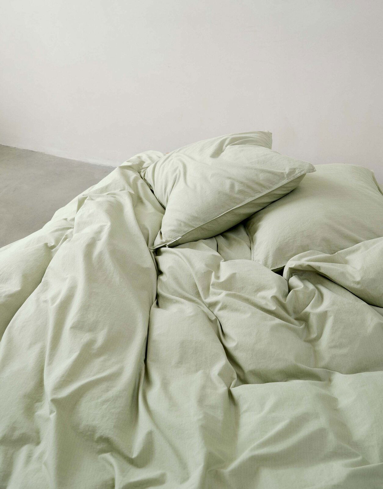 Grüne Bettwäsche 135x200cm, aus der Vogelperspektive fotografiert, auf einem Bett arrangiert.