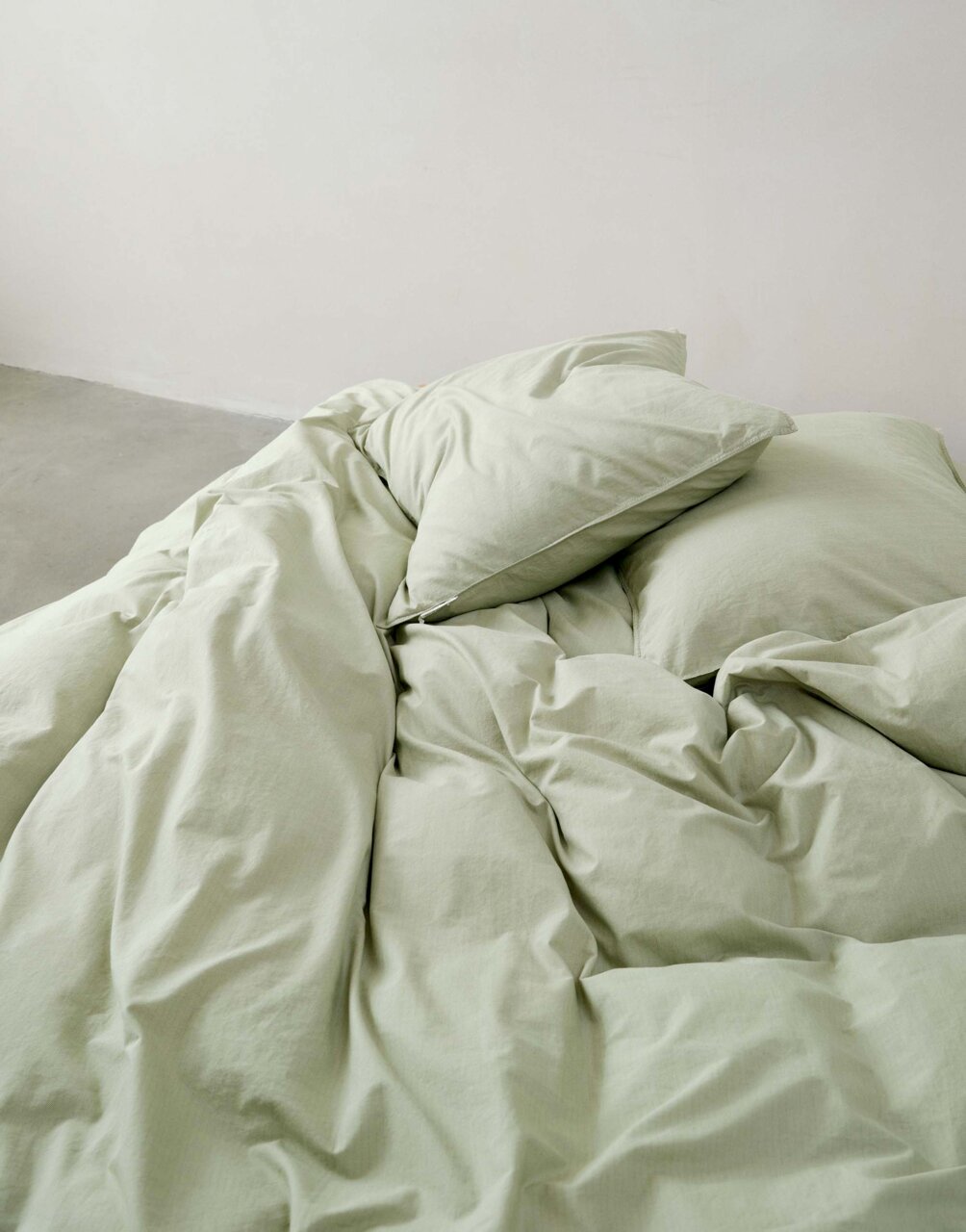 Grüne Bettwäsche 135x200cm, aus der Vogelperspektive fotografiert, auf einem Bett arrangiert.