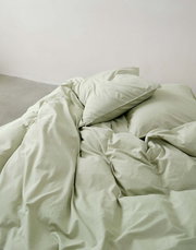 Grüne Bettwäsche 135x200cm, aus der Vogelperspektive fotografiert, auf einem Bett arrangiert.