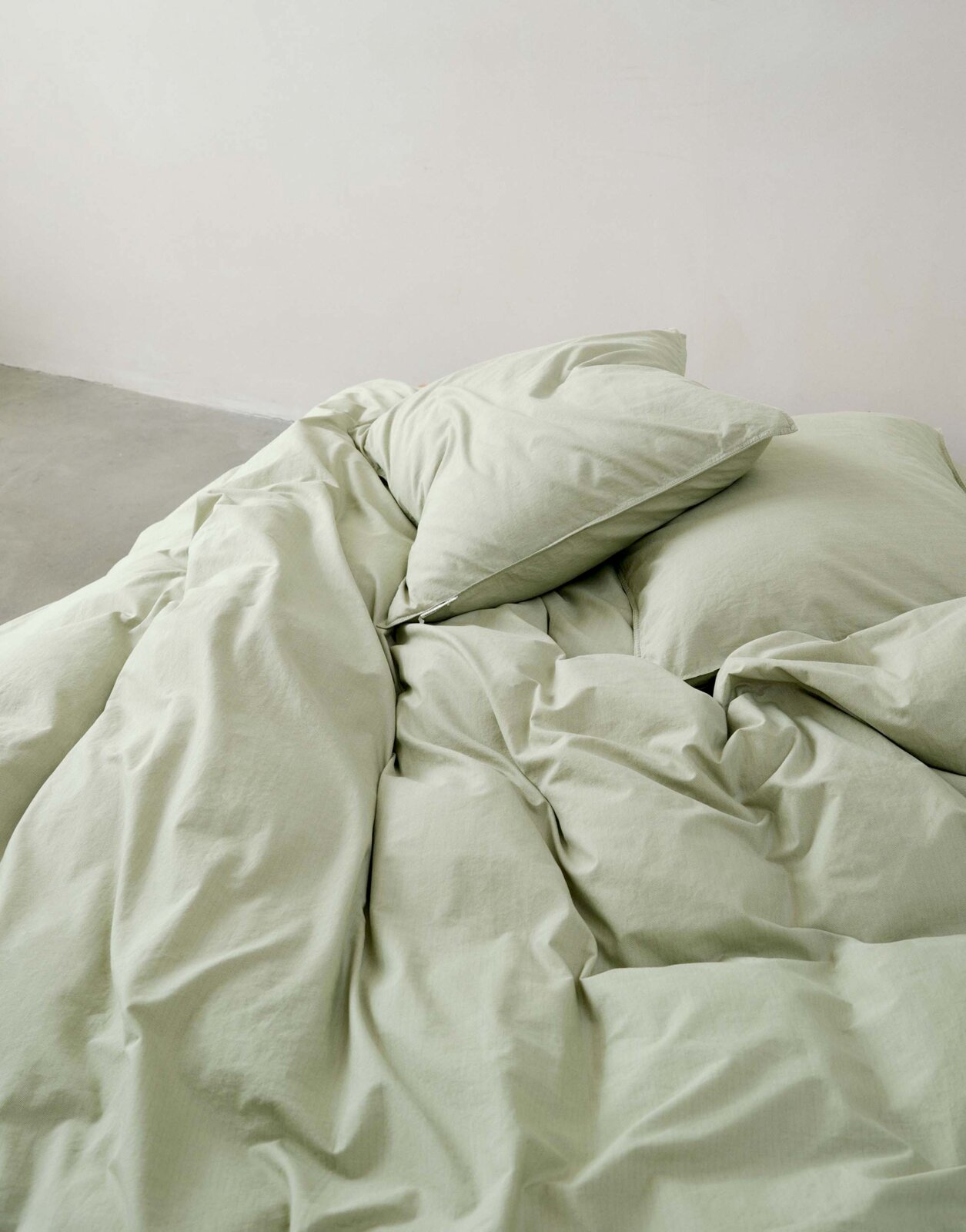 Groen beddengoed van 135 x 200 cm, gefotografeerd vanuit vogelperspectief, opgemaakt op een bed.
