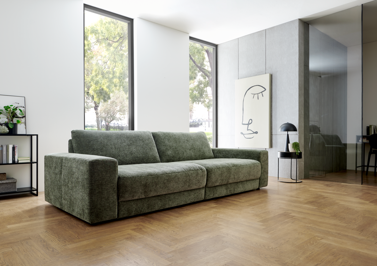 Grünes Megasofa in modernem Wohnzimmer, seitliche Perspektive