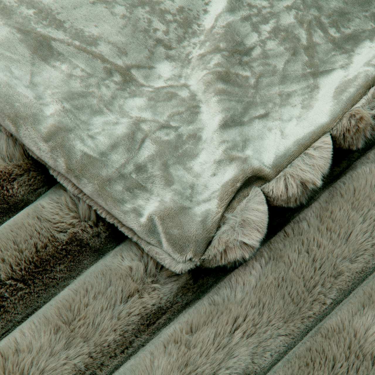 Detailansicht einer luxuriösen Felldecke mit weicher, plüschiger Textur in einem sanften Grauton.