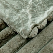 Detailansicht einer luxuriösen Felldecke mit weicher, plüschiger Textur in einem sanften Grauton.