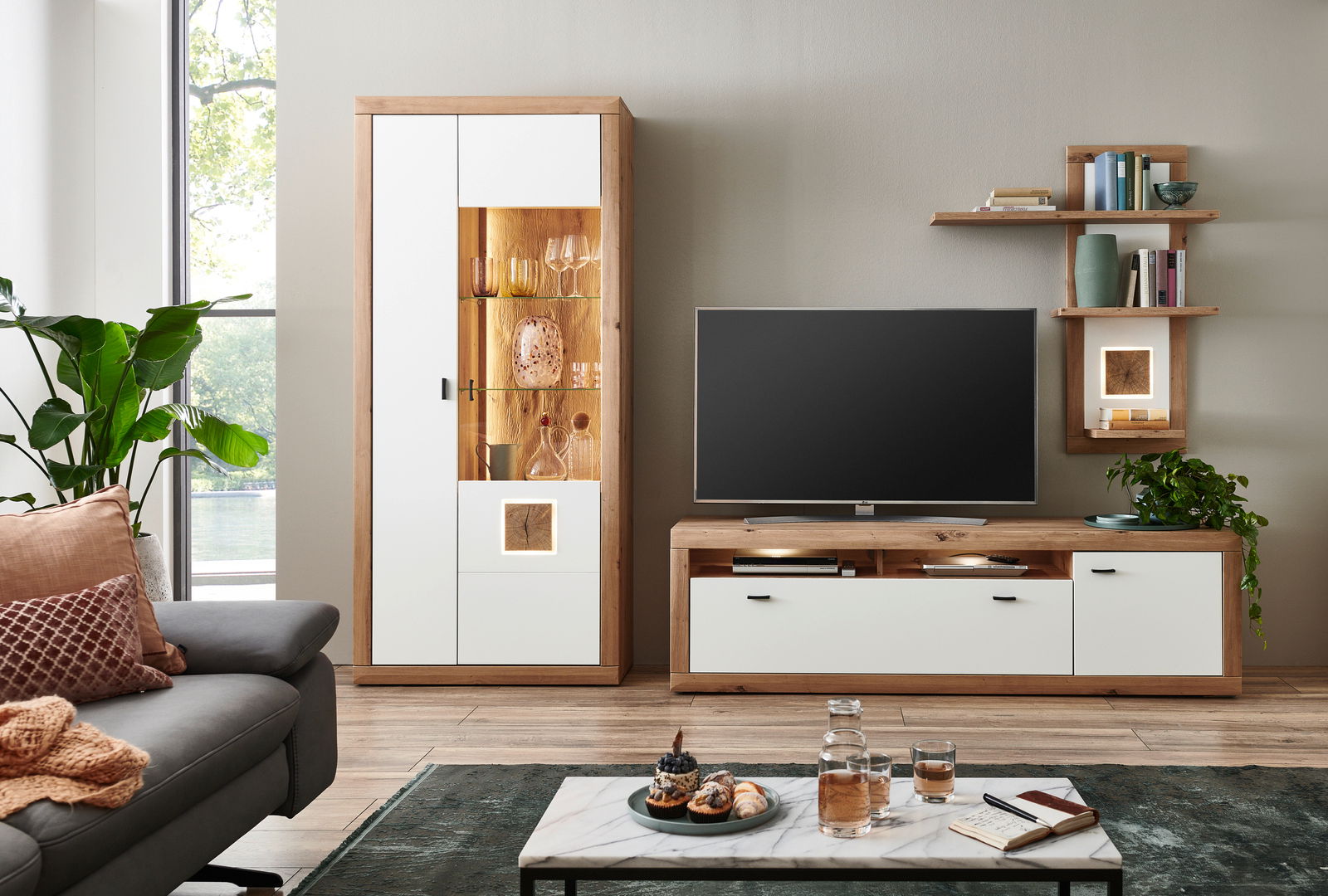 Moderne Wandkombination BORKUM in hellem Holz und Weiß, bestehend aus einem hohen Schrank mit Glaseinsatz, einem TV-Board und einem Wandregal. Perspektive: Frontalansicht.