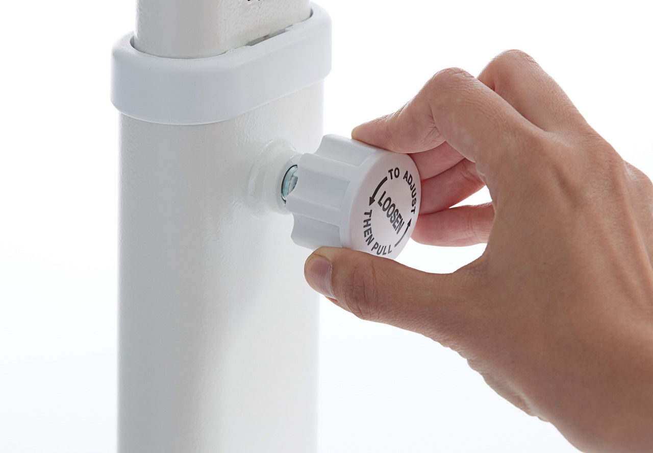 Nahaufnahme einer Hand, die einen weißen Einstellknopf an einem Schreibtischbein dreht, um die Höhe zu verstellen.