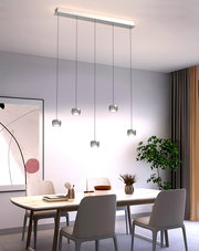 Moderne LED-Pendelleuchte mit fünf hängenden Leuchten über einem Esstisch, seitliche Perspektive