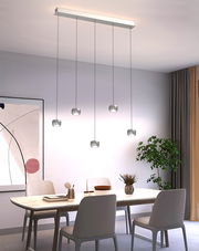 Moderne LED-Pendelleuchte mit fünf hängenden Leuchten über einem Esstisch, seitliche Perspektive