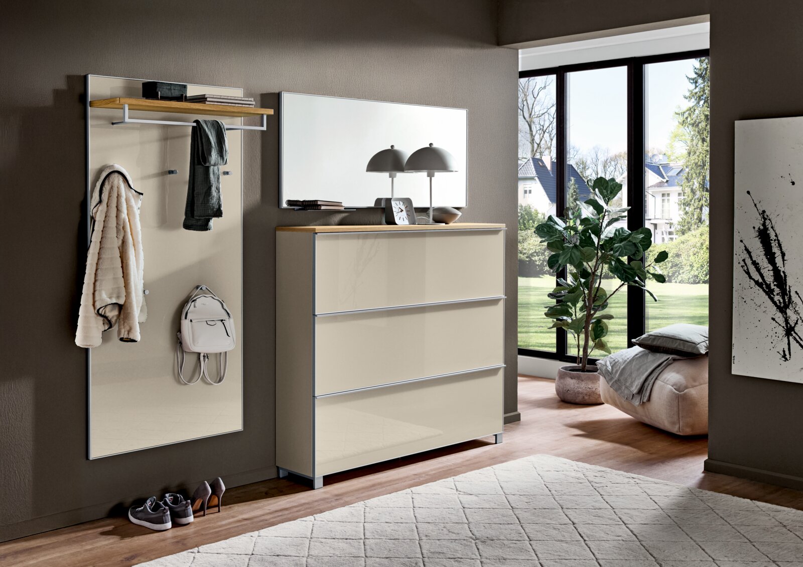 Moderne Garderoben-Kombination im Flur: Wandpaneel mit Hutablage, Kleiderhaken und Spiegel sowie passende Kommode in Beige mit Holzablage, frontal aus leicht schräger Perspektive fotografiert.
