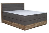 Boxspringbett in seitlicher Perspektive mit grauem Polster und Holzrahmen