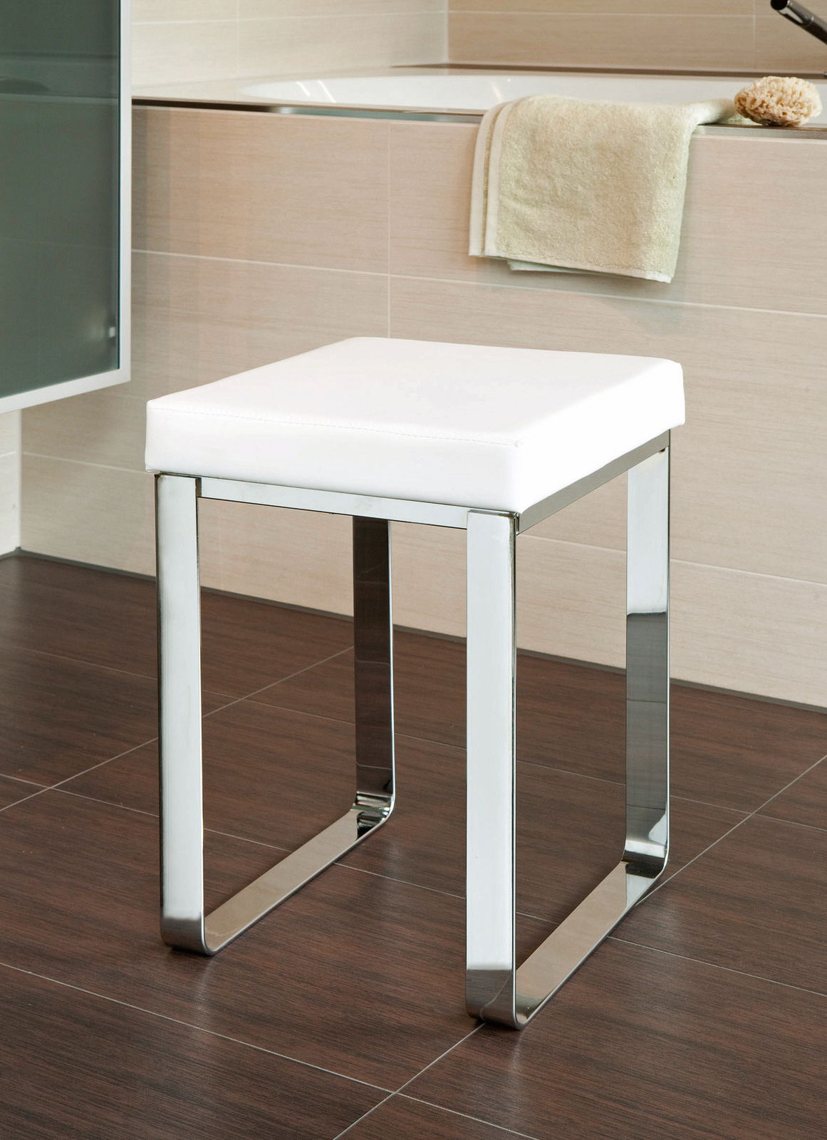 Moderner Badhocker mit weißem Sitzpolster und verchromtem Gestell, seitliche Perspektive.