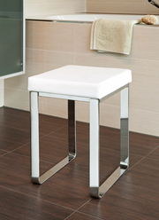 Moderner Badhocker mit weißem Sitzpolster und verchromtem Gestell, seitliche Perspektive.