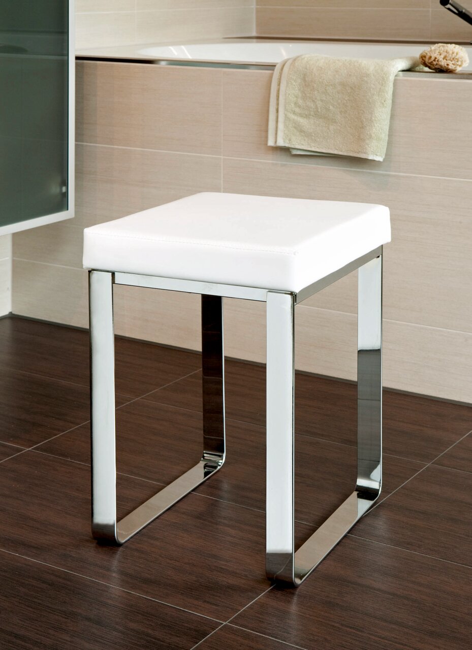 Moderner Badhocker mit weißem Sitzpolster und verchromtem Gestell, seitliche Perspektive.