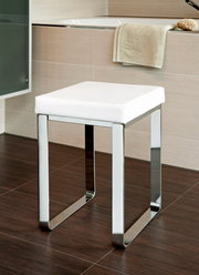 Moderner Badhocker mit weißem Sitzpolster und verchromtem Gestell, seitliche Perspektive.