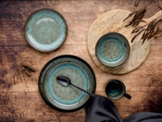 Keramik-Geschirrset in Blaugrün mit Tellern, Schale und Tasse auf rustikalem Holztisch, Draufsicht von oben