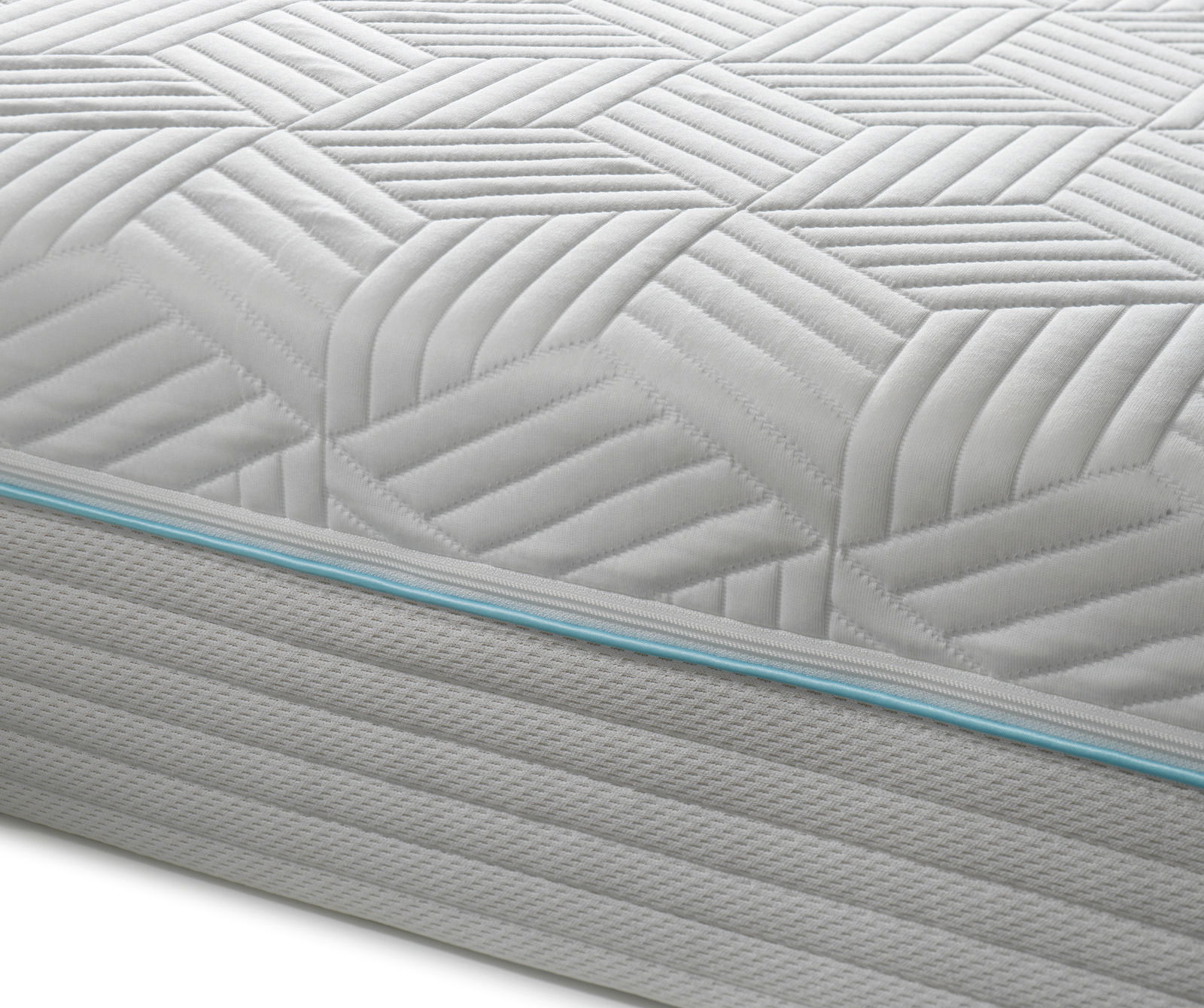Nahaufnahme einer Gel-Kaltschaummatratze mit geometrischem Muster und blauer Ziernaht an der Seite, seitliche Perspektive