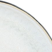 Nahaufnahme eines grauen Tellers mit feiner Textur und dunklem Rand, von oben betrachtet.