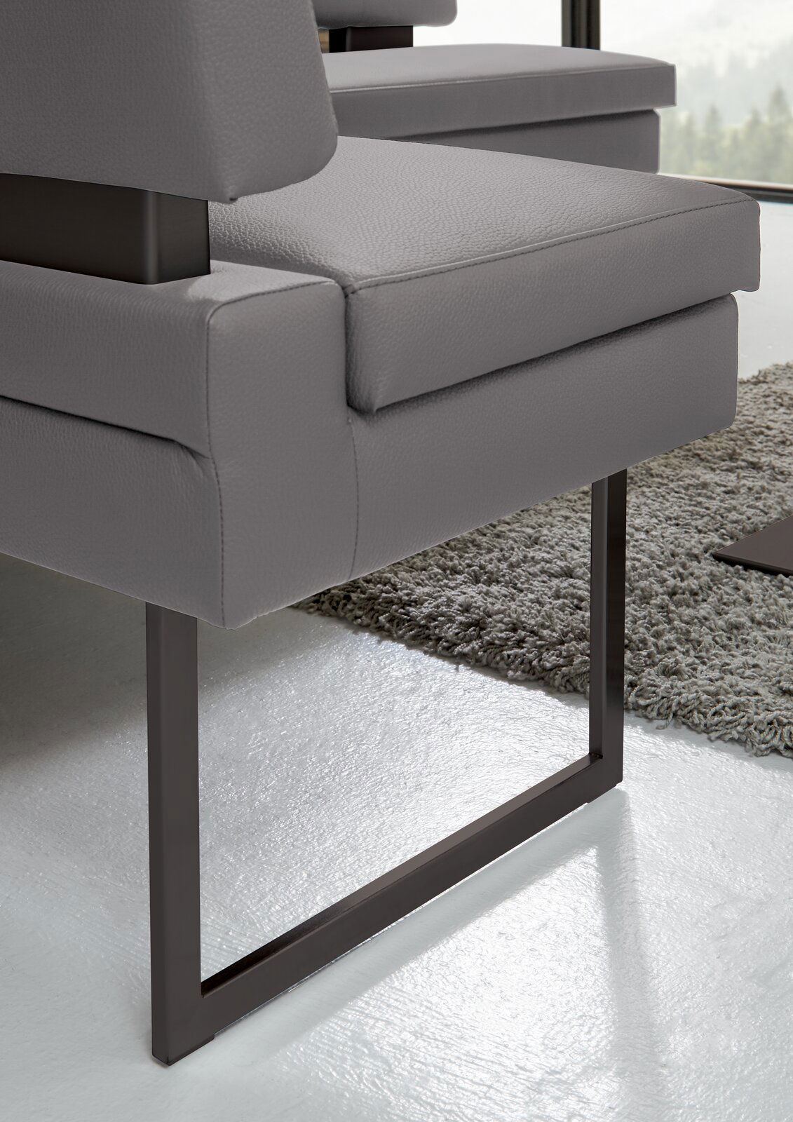 Nahaufnahme einer modernen grauen Eckbank mit Metallbeinen, seitliche Perspektive.