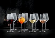 Mehrere geriffelte Weingläser mit Stiel auf dunklem Untergrund, teils mit Rotwein, Aperol-Spritz, Weißwein und Rosé gefüllt, frontal in leichter Seitenperspektive fotografiert.