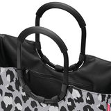 Nahaufnahme einer Tasche mit schwarzem und grauem Leopardenmuster und schwarzen Griffen, Ansicht von oben.